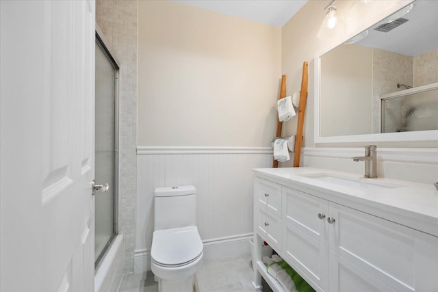 700 NE 20th Ln, Boynton Beach, FL 33435 - full bathroom with a wainscoted wall, visible vents, toilet, enclosed tub / shower combo, and vanity