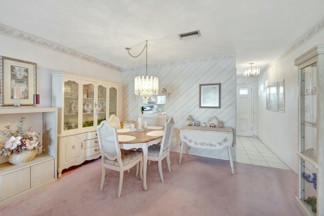 dining area featuring visible vents, a notable chandelier, washer and dryer, light tile patterned flooring, and light colored carpet