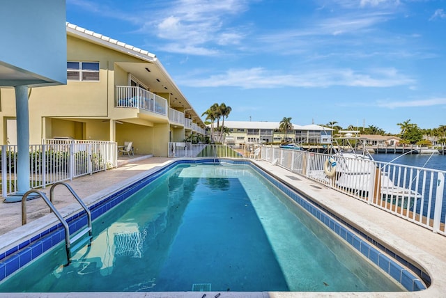 pool featuring a patio area, fence, and a water view