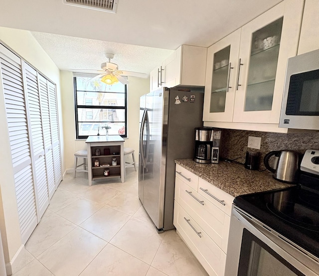 7365 NW 18th St Unit 107, Margate, FL 33063 - kitchen with appliances with stainless steel finishes, glass insert cabinets, white cabinets, tasteful backsplash, and a ceiling fan