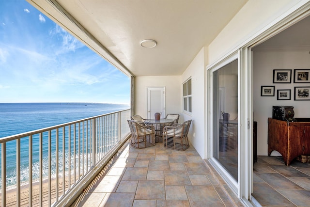 balcony featuring a view of the beach and a water view