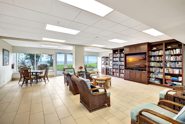 living room with light tile patterned flooring and a paneled ceiling