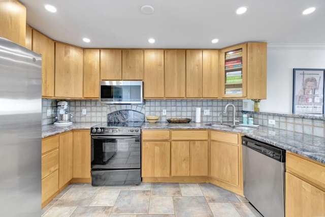 kitchen with a sink, decorative backsplash, light stone countertops, and appliances with stainless steel finishes