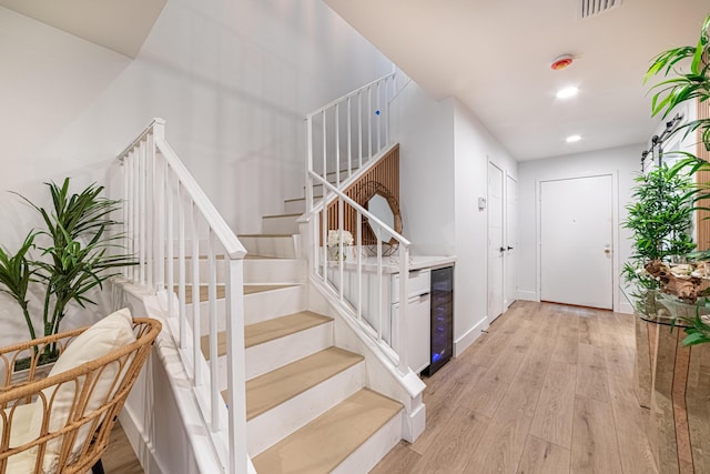 stairs with visible vents, beverage cooler, wood finished floors, recessed lighting, and baseboards