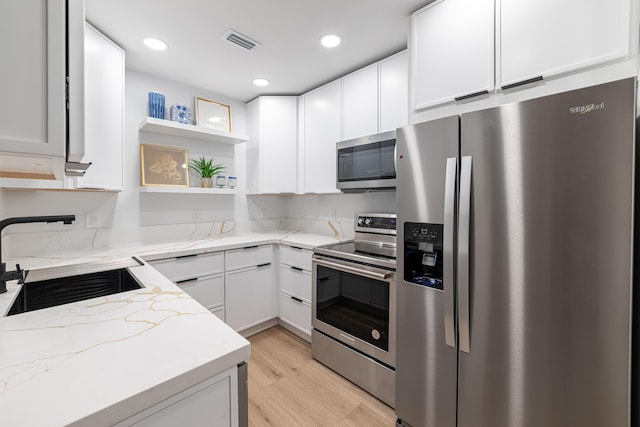 kitchen featuring visible vents, a sink, light stone countertops, stainless steel appliances, and open shelves