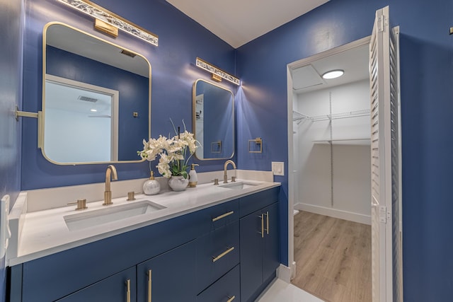 bathroom featuring double vanity, visible vents, wood finished floors, and a sink