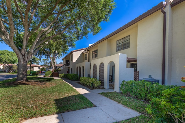 view of home's exterior with a yard, central AC unit, and stucco siding