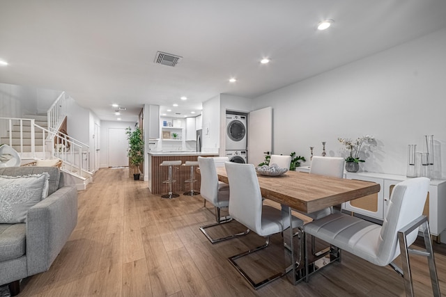 dining space with visible vents, stacked washing maching and dryer, recessed lighting, stairs, and light wood-type flooring