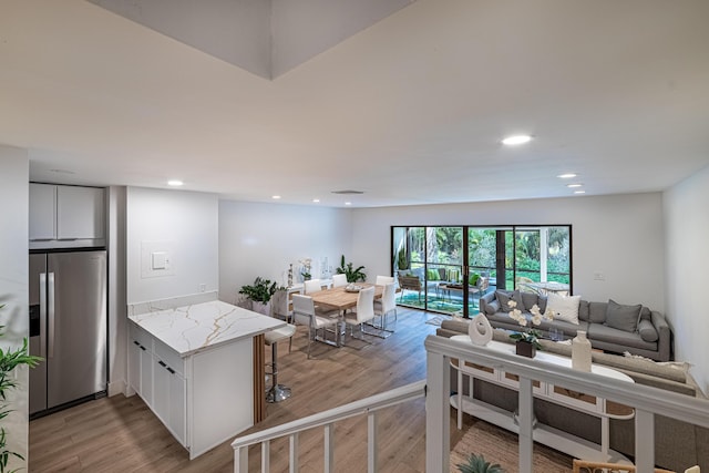 kitchen featuring white cabinets, a peninsula, light wood-style floors, and stainless steel fridge with ice dispenser