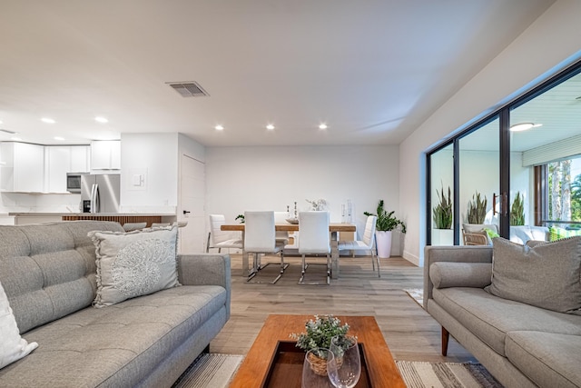 living room featuring recessed lighting, visible vents, and light wood finished floors