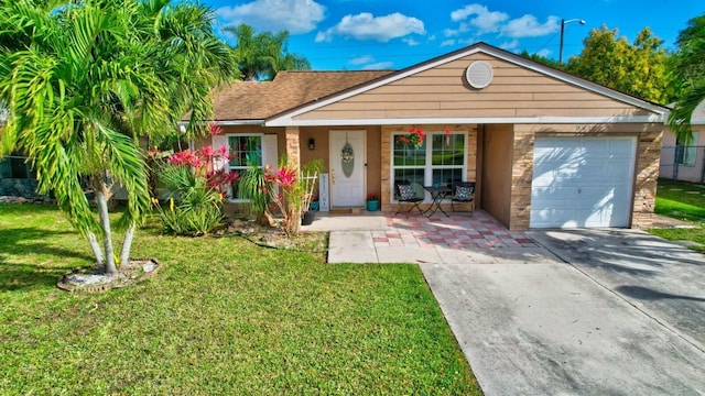 single story home with covered porch, concrete driveway, an attached garage, a front yard, and roof with shingles