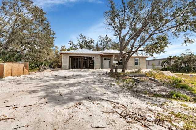 view of front of home featuring a garage, fence, metal roof, and stucco siding