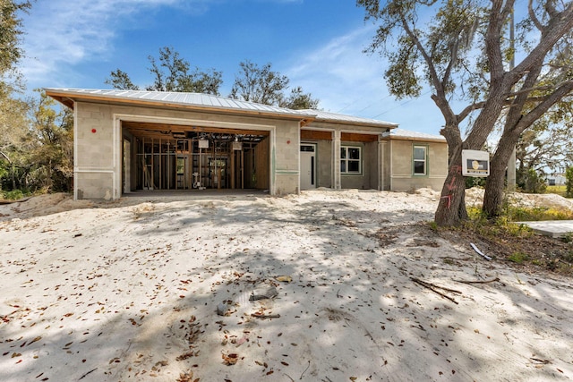 view of front facade with concrete block siding, an attached garage, and metal roof