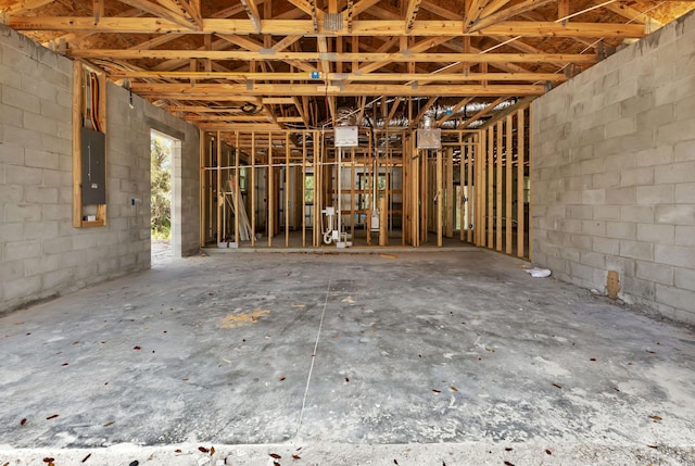 misc room featuring concrete block wall and electric panel