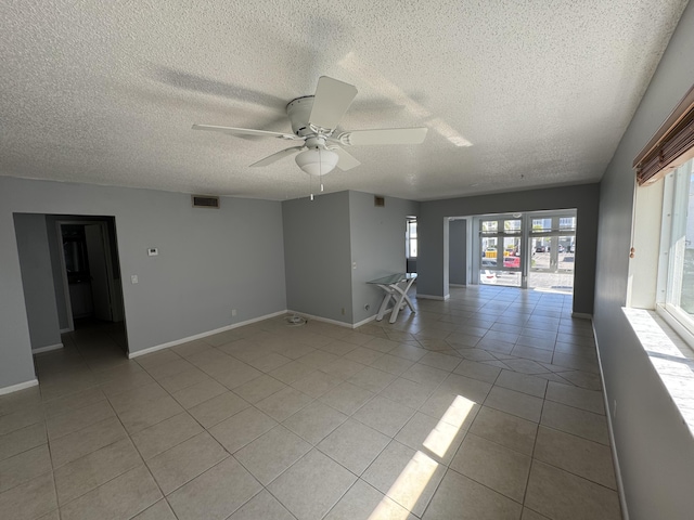 unfurnished room featuring light tile patterned flooring, visible vents, baseboards, and a ceiling fan