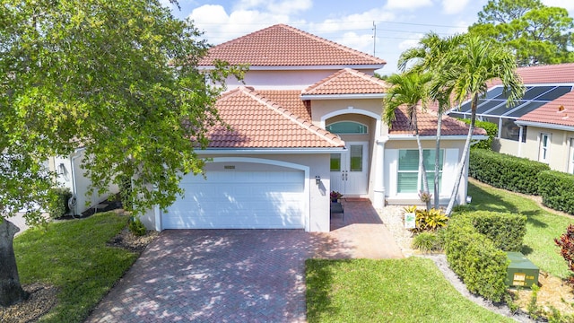 mediterranean / spanish-style home featuring a tiled roof, decorative driveway, a garage, and stucco siding