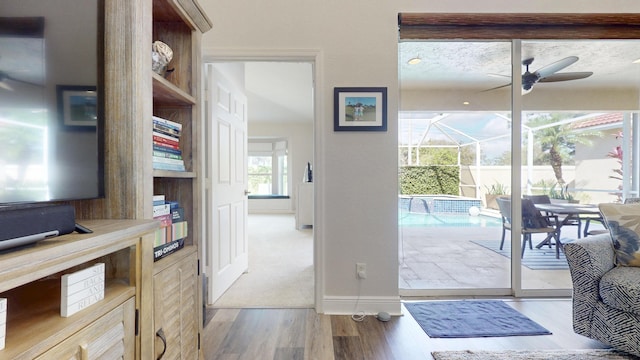 entryway featuring baseboards, ceiling fan, and light wood finished floors