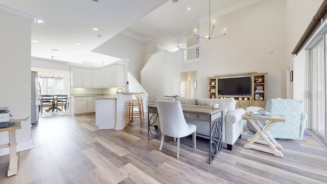 living area with an inviting chandelier, recessed lighting, light wood-style floors, and a towering ceiling