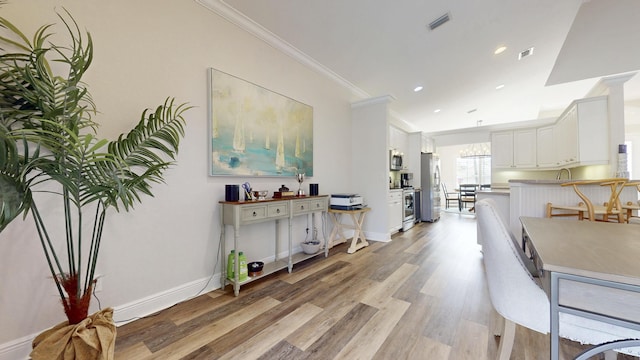 interior space featuring visible vents, light wood-style flooring, crown molding, and baseboards