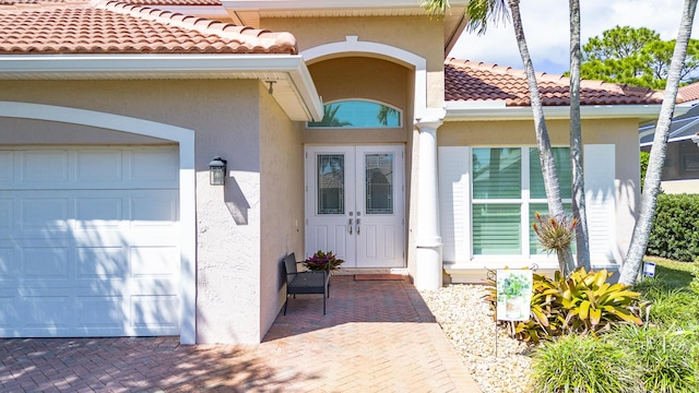 entrance to property featuring stucco siding, a garage, and a tiled roof