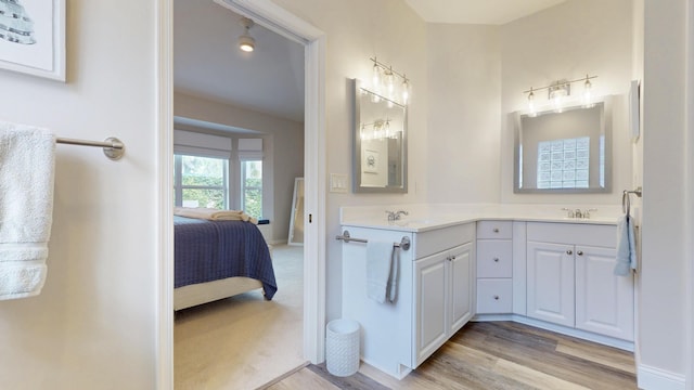 ensuite bathroom featuring a sink, double vanity, wood finished floors, and connected bathroom