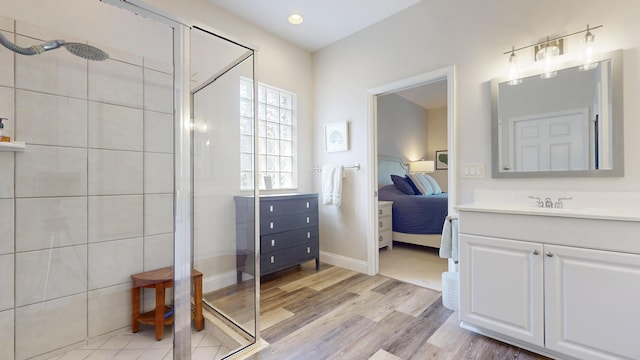 ensuite bathroom featuring vanity, wood finished floors, baseboards, a shower stall, and connected bathroom