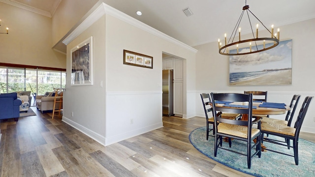 dining room with a notable chandelier, crown molding, visible vents, and wood finished floors