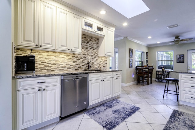 kitchen with light tile patterned floors, ornamental molding, a sink, dishwasher, and backsplash