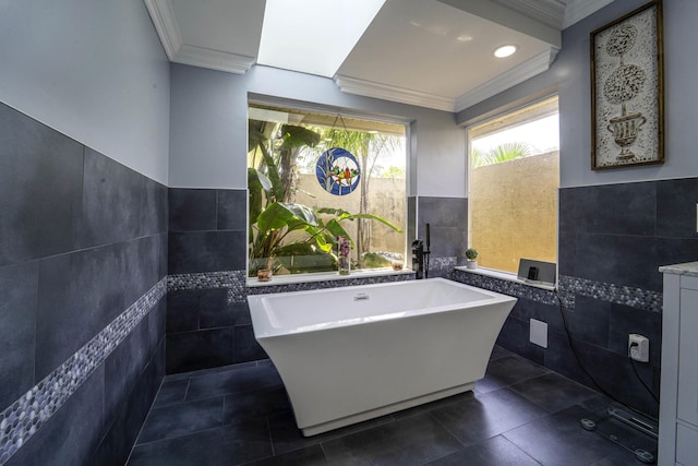 full bathroom with a freestanding tub, ornamental molding, tile patterned flooring, wainscoting, and tile walls