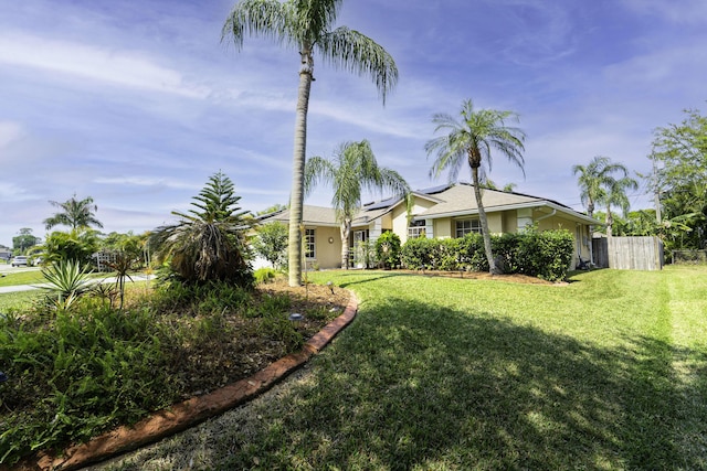 view of front of property with a front lawn, fence, roof mounted solar panels, and stucco siding