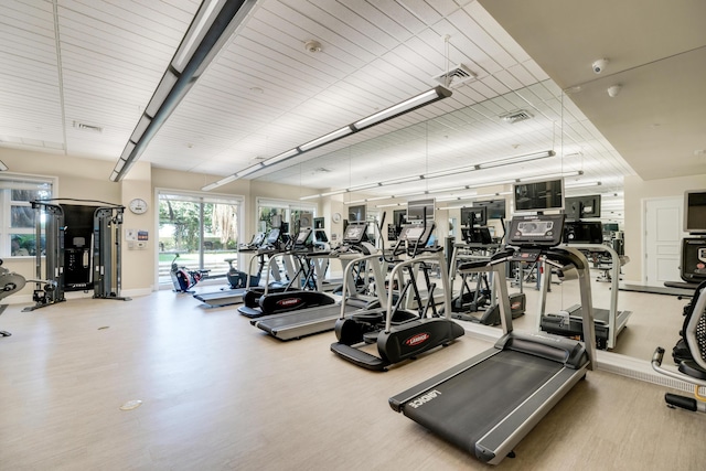 exercise room featuring wood finished floors, visible vents, and baseboards