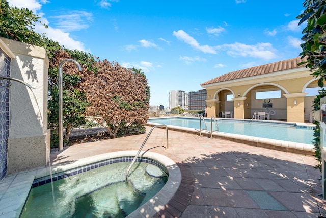 community pool with a hot tub and a patio