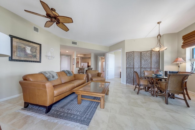 living area with tile patterned flooring, visible vents, baseboards, and a ceiling fan