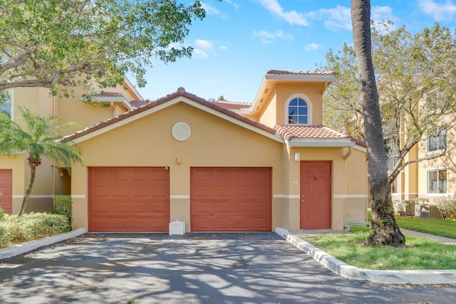 500 Scotia Dr Unit 106, Hypoluxo, FL 33462 - mediterranean / spanish-style home featuring a tile roof, central AC unit, aphalt driveway, a garage, and stucco siding