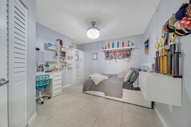 500 Scotia Dr Unit 106, Hypoluxo, FL 33462 - bedroom featuring an inviting chandelier, a textured ceiling, and light tile patterned floors
