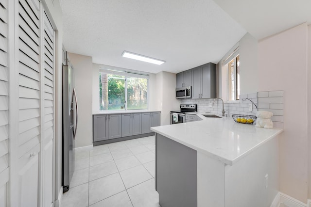 500 Scotia Dr Unit 106, Hypoluxo, FL 33462 - kitchen featuring gray cabinets, a sink, a peninsula, tasteful backsplash, and appliances with stainless steel finishes