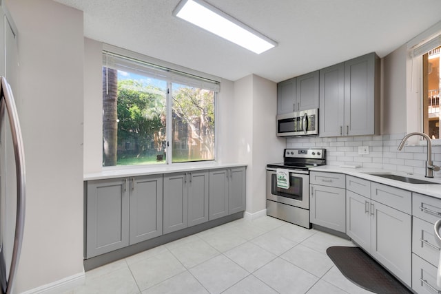 500 Scotia Dr Unit 106, Hypoluxo, FL 33462 - kitchen featuring gray cabinets, a sink, baseboards, decorative backsplash, and appliances with stainless steel finishes
