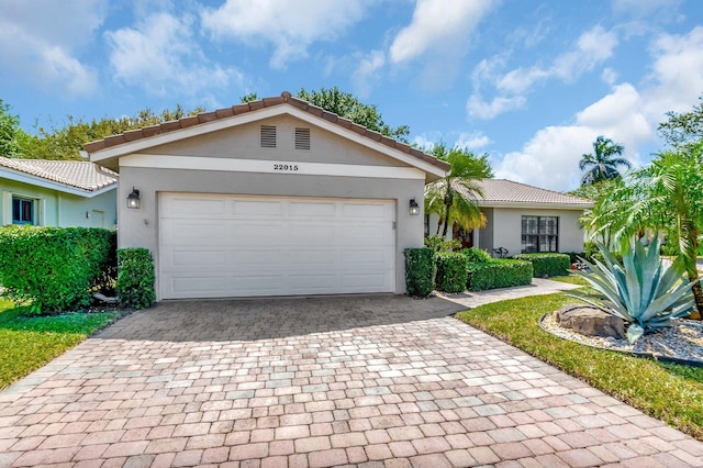 single story home with stucco siding, decorative driveway, an attached garage, and a tile roof