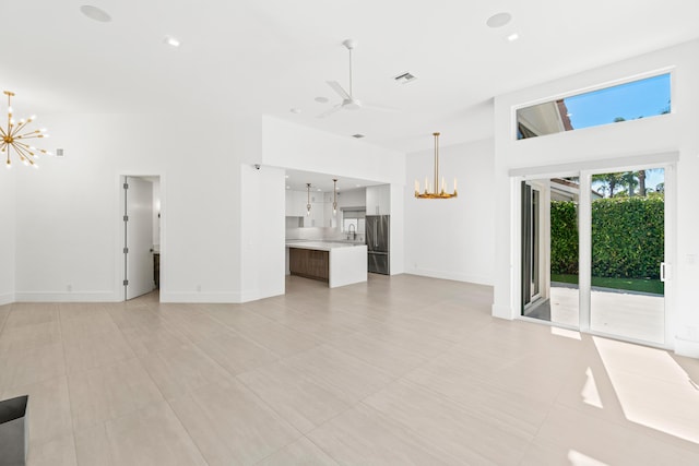 unfurnished living room featuring visible vents, recessed lighting, ceiling fan with notable chandelier, and baseboards