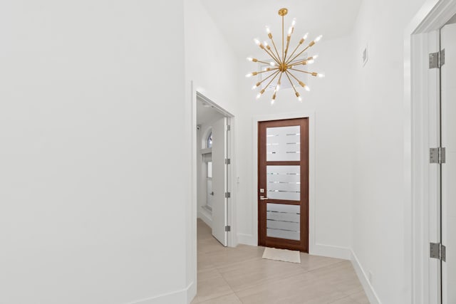 entrance foyer with an inviting chandelier, light tile patterned flooring, and baseboards