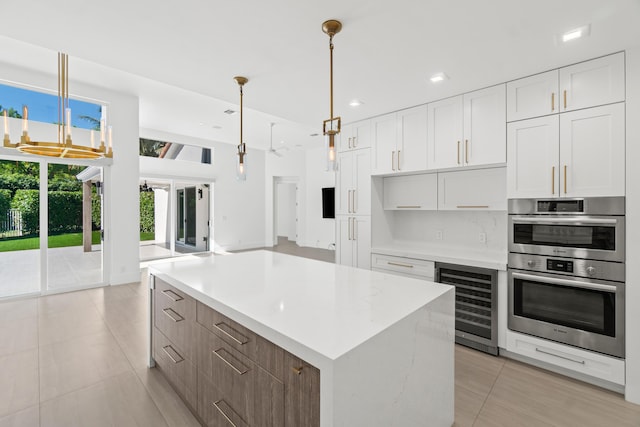 kitchen with a center island, wine cooler, double oven, light countertops, and white cabinets