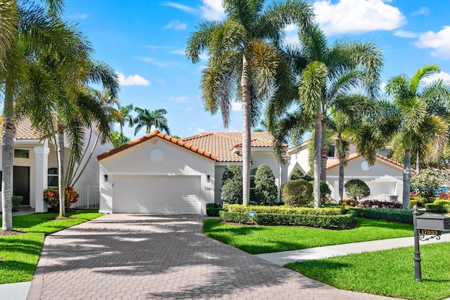 mediterranean / spanish house featuring stucco siding, a front lawn, decorative driveway, an attached garage, and a tiled roof