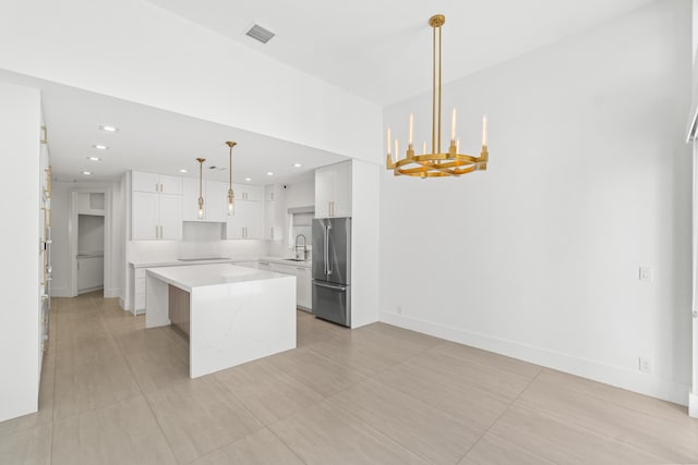 kitchen featuring visible vents, a notable chandelier, a sink, a center island, and freestanding refrigerator