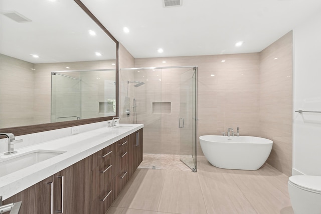 bathroom with a sink, a soaking tub, a stall shower, and double vanity