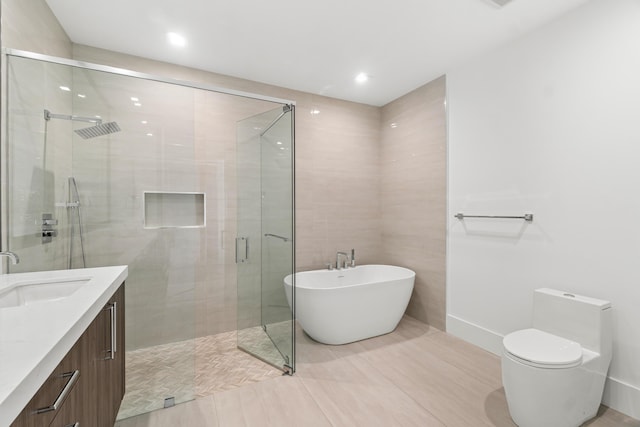 bathroom featuring toilet, a stall shower, vanity, and a freestanding tub