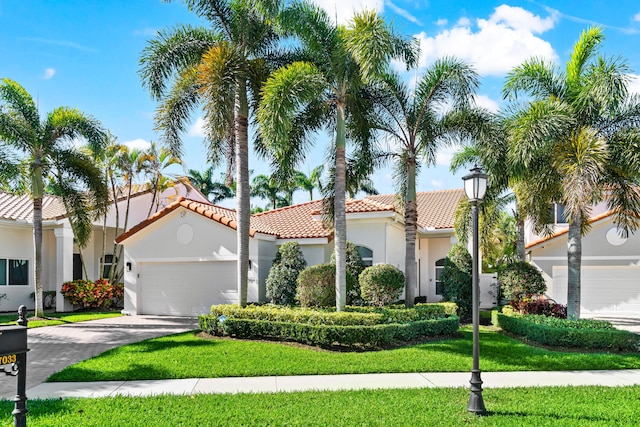 mediterranean / spanish-style house with a front yard, driveway, stucco siding, a garage, and a tiled roof