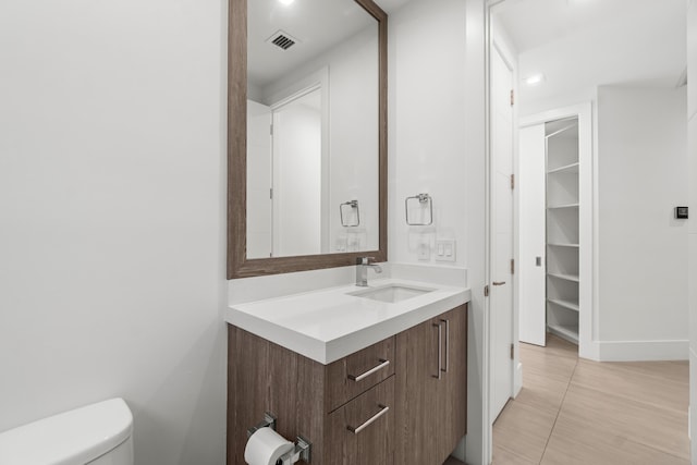 bathroom featuring vanity, toilet, and visible vents