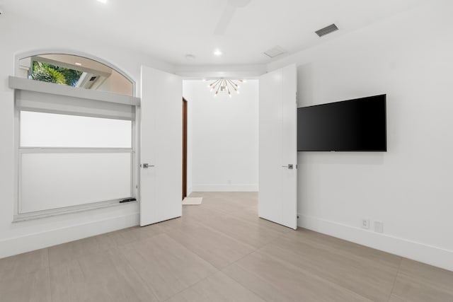 spare room featuring ceiling fan with notable chandelier, baseboards, and visible vents