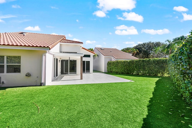 back of house featuring a tiled roof, stucco siding, a yard, and a patio area