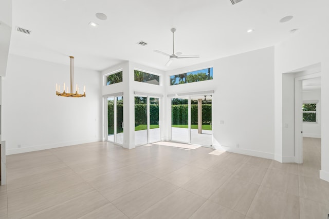 unfurnished room featuring visible vents, ceiling fan with notable chandelier, baseboards, and a towering ceiling